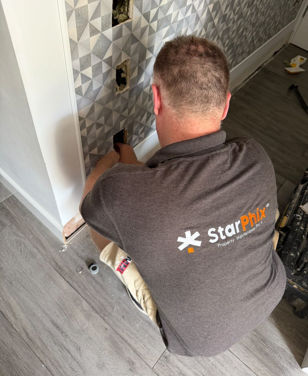 A StarPhix tradesman in branded workwear repairing a wall